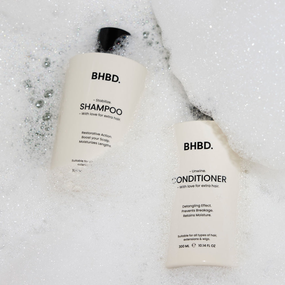 BHBD hair care products, shampoo and conditioner covered in bath foam. 