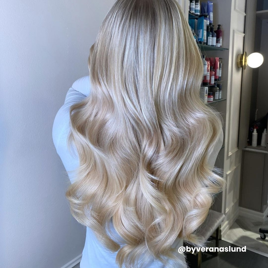 Woman in long, curly blonde hair created with BHBD tape extensions.